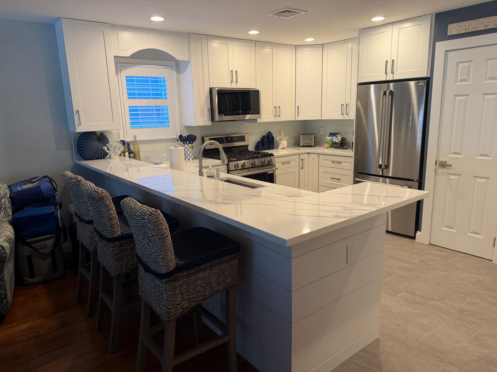 Finished kitchen remodel with white shaker cabinets, quartz waterfall island, and new stainless appliances completed by HRF Painting & Construction in Avalon, NJ.