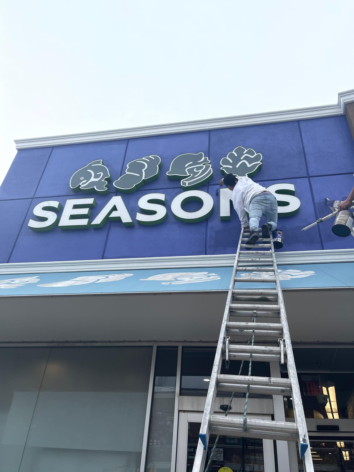 Commercial retail building exterior after repaint, with a navy blue upper band and tan lower panels, in Philadelphia, PA.