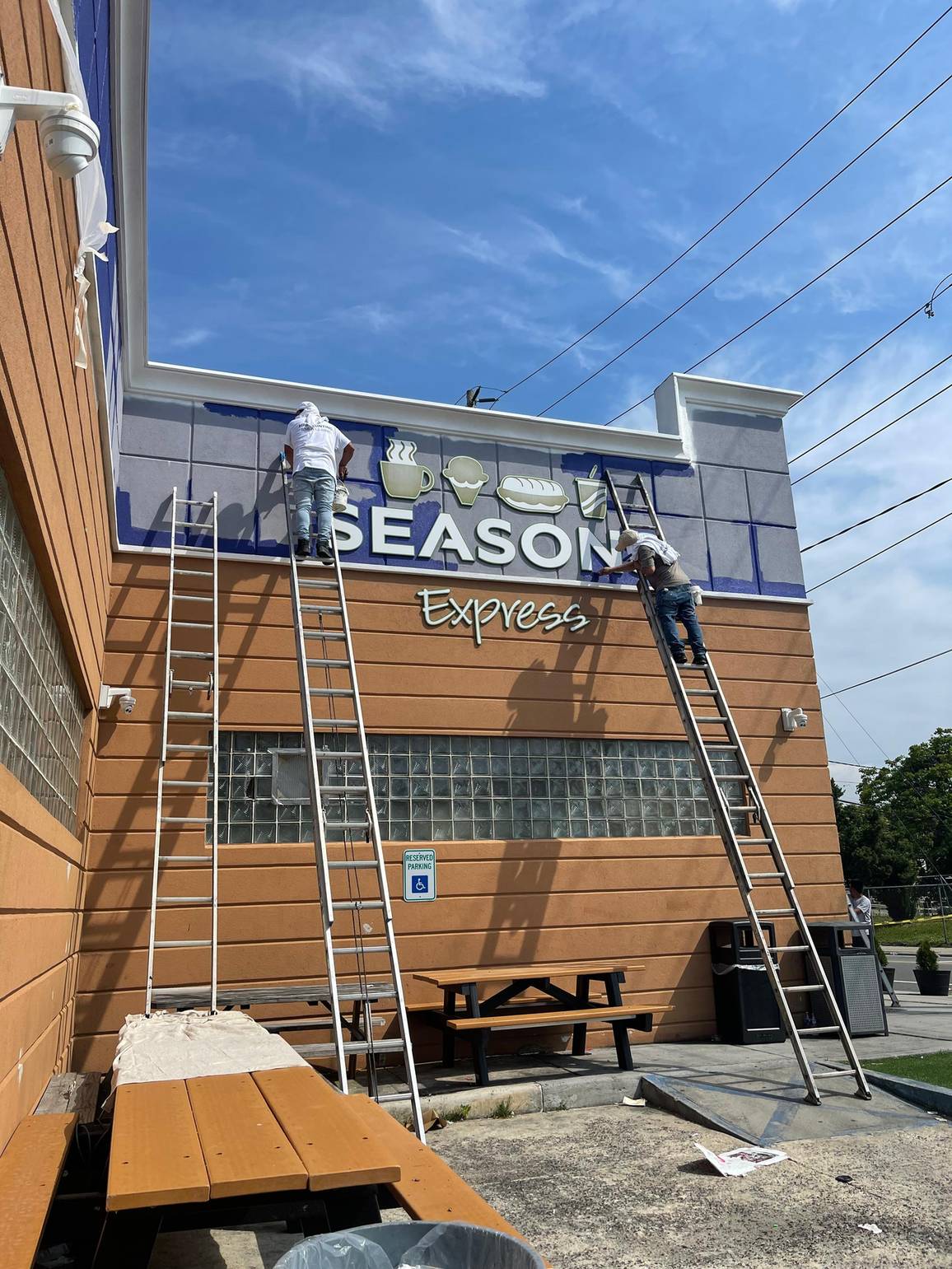 HRF crew painting a retail storefront facade from ladders during a commercial exterior repaint