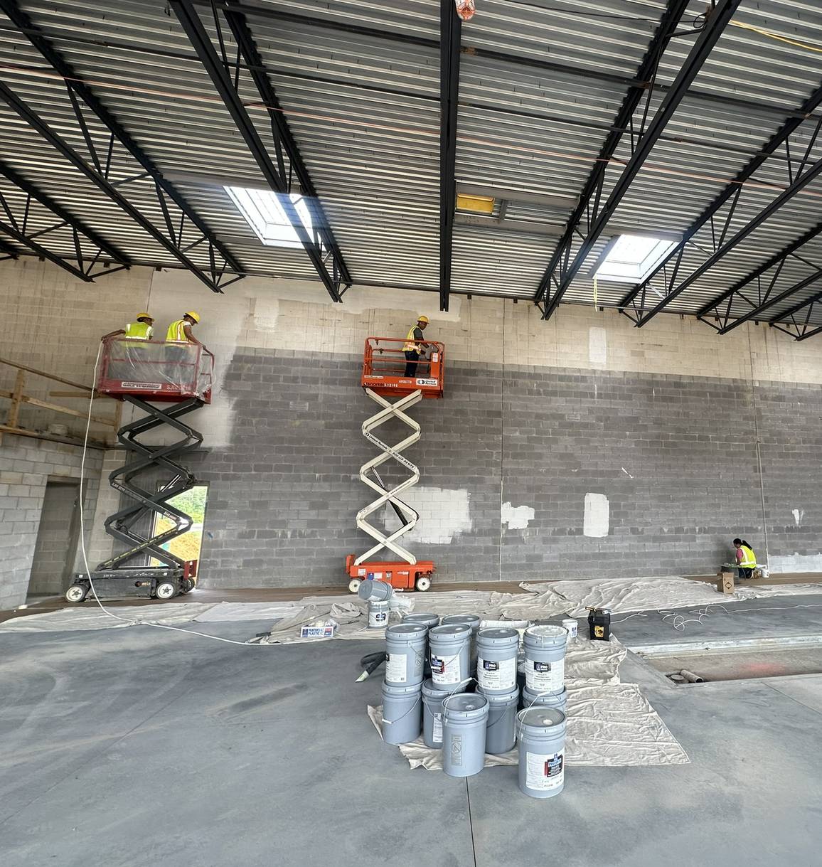 HRF crew using scissor lifts to paint high block walls in a large commercial service bay