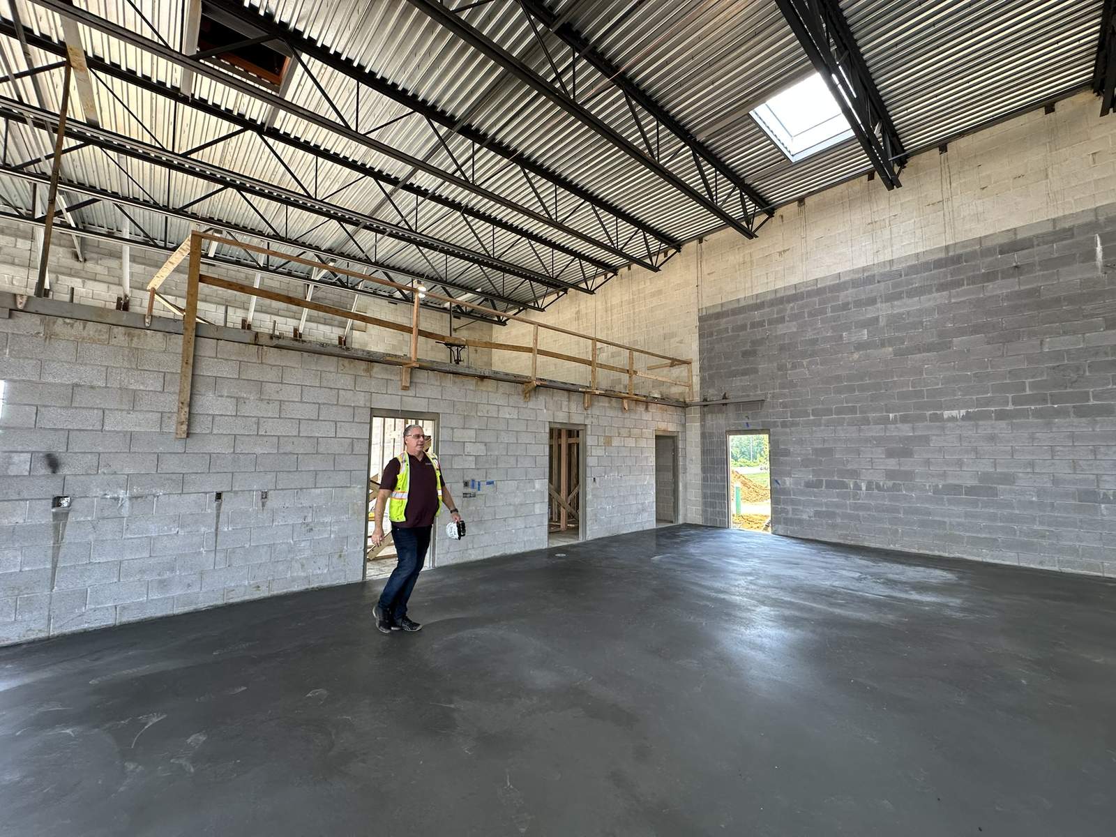 Unpainted concrete block walls and exposed steel roof deck before commercial painting at a tire store service bay