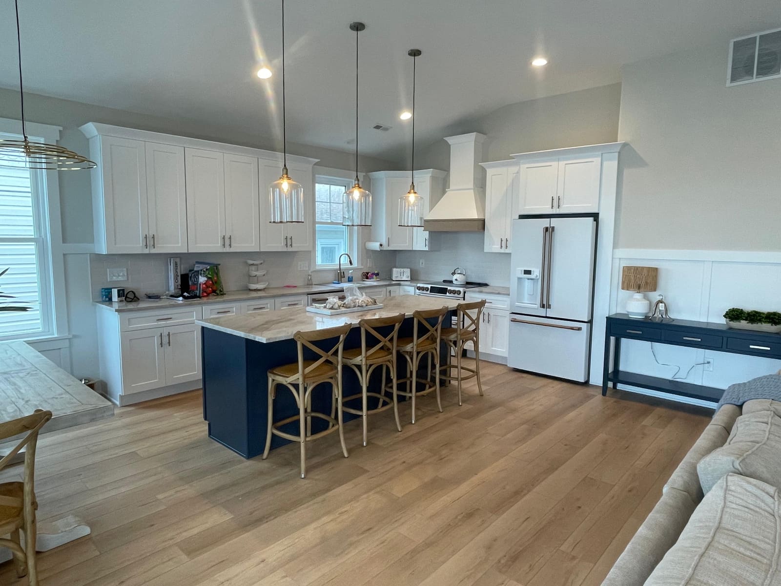 Finished kitchen remodel with white cabinets, navy island, and brass pendant lighting completed by HRF Painting & Construction in Ocean City, NJ.