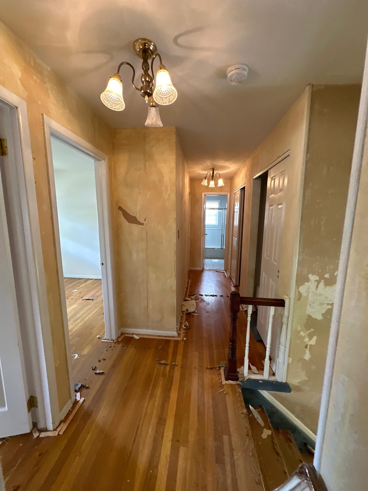Hallway and staircase before renovation, with damaged wallpaper and worn paint, in Moorestown, NJ.