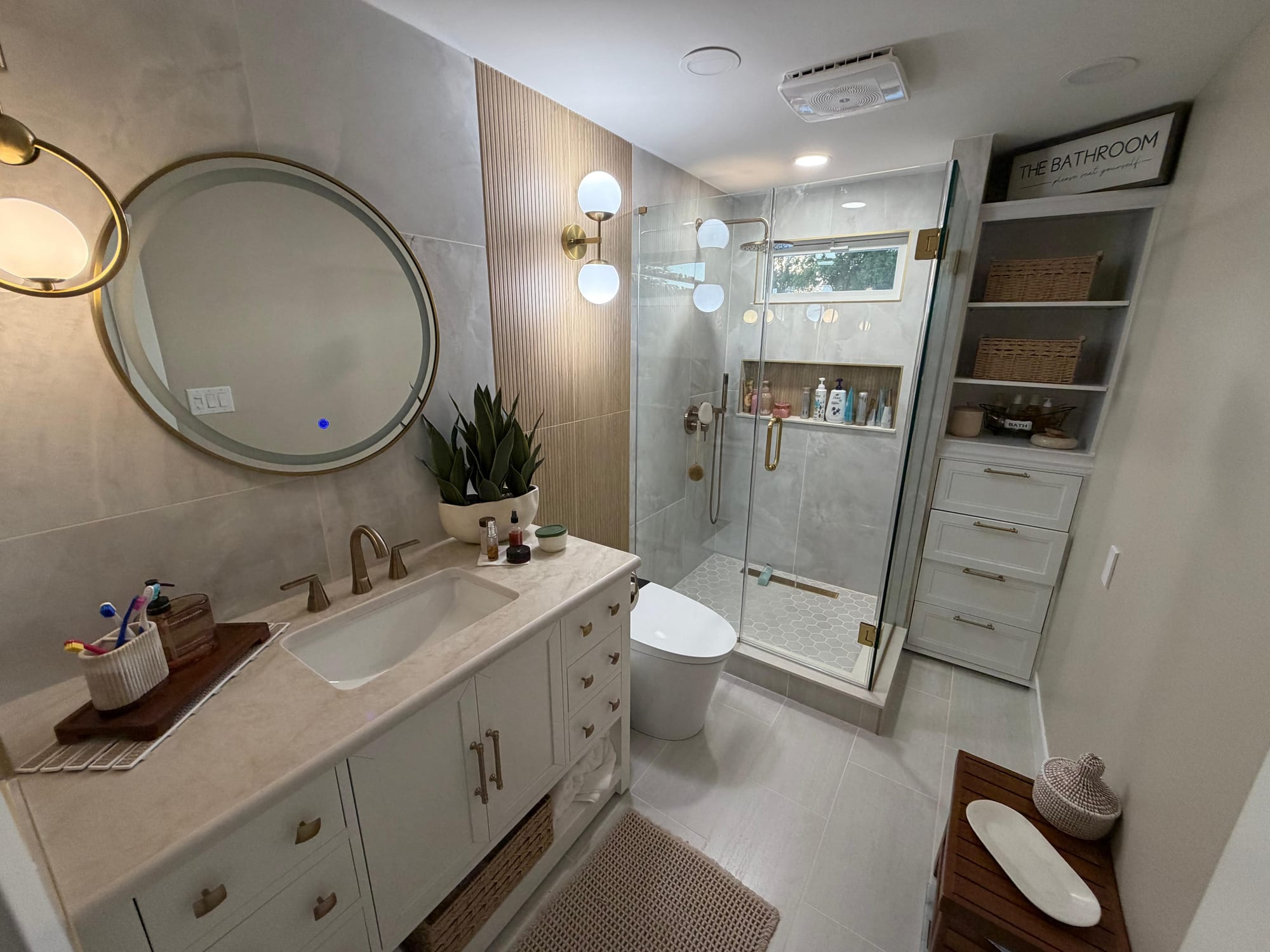Finished full bathroom remodel with glass shower enclosure, hexagon tile, and round mirror in Voorhees, NJ.